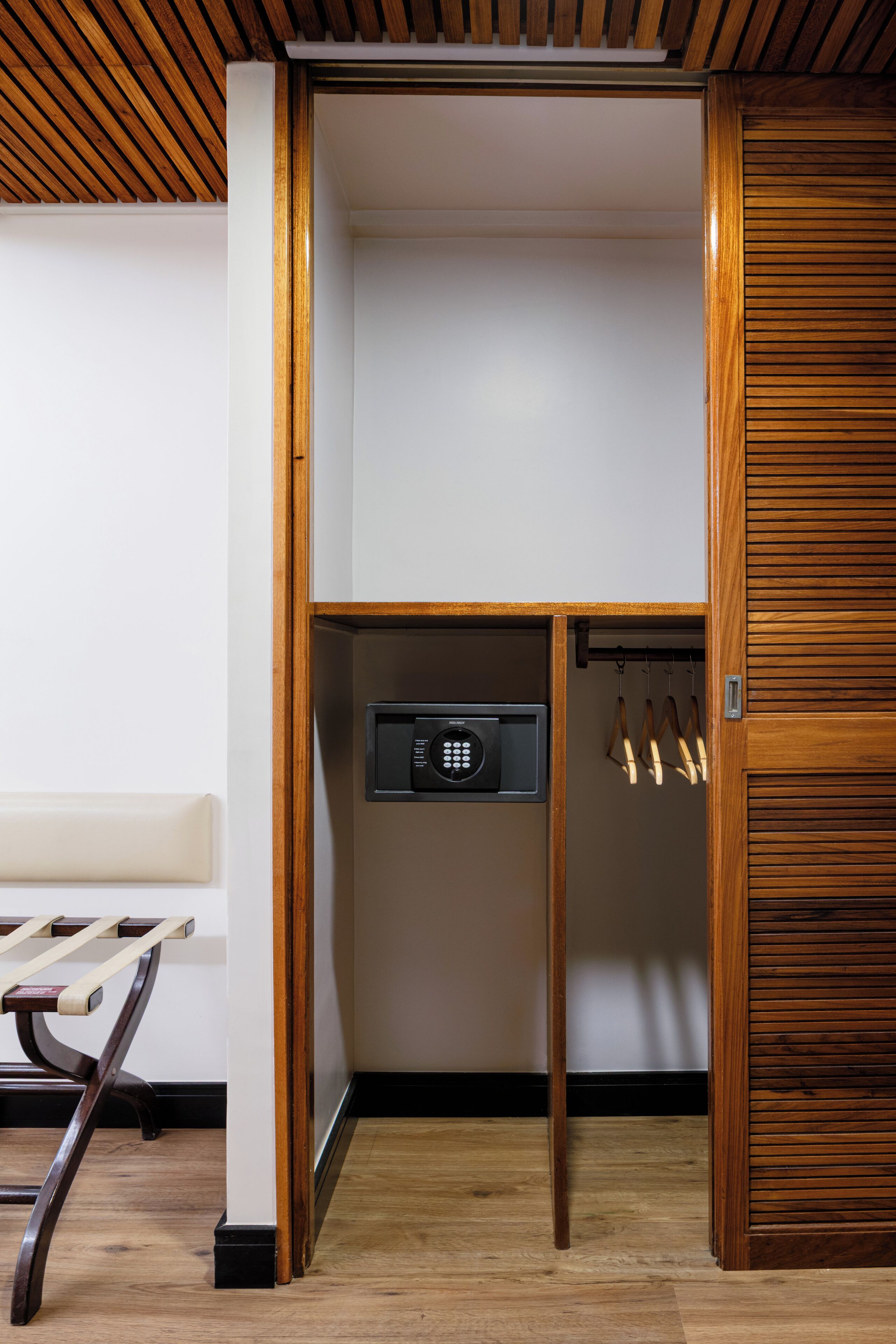 A wooden closet with a built-in safe and a coat rack.