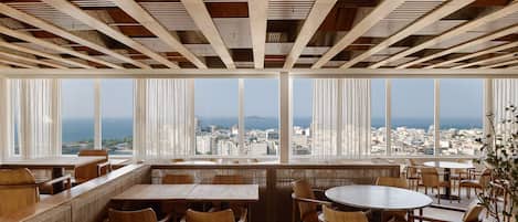 Un comedor moderno con mobiliario de madera y amplias ventanas que ofrecen vistas a la ciudad.