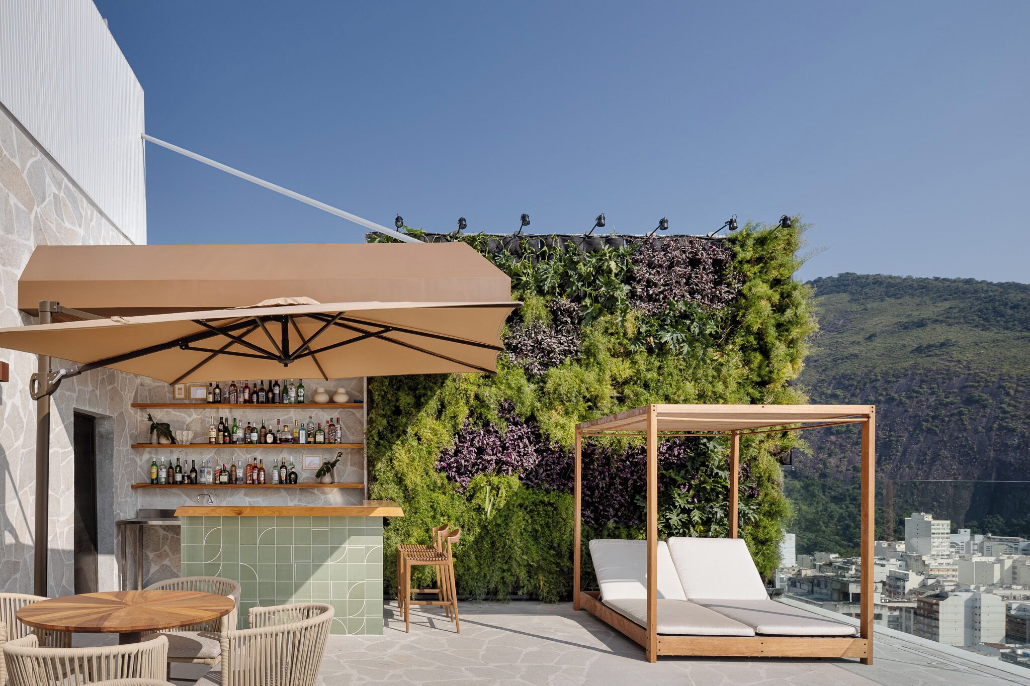 Un espace bar extérieur avec une table en bois, des chaises et un coin salon confortable aménagé sous une tonnelle.