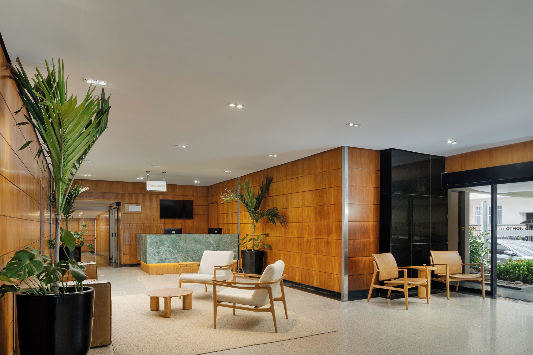 A reception area with wooden paneling, a marble reception desk, and several seating arrangements.