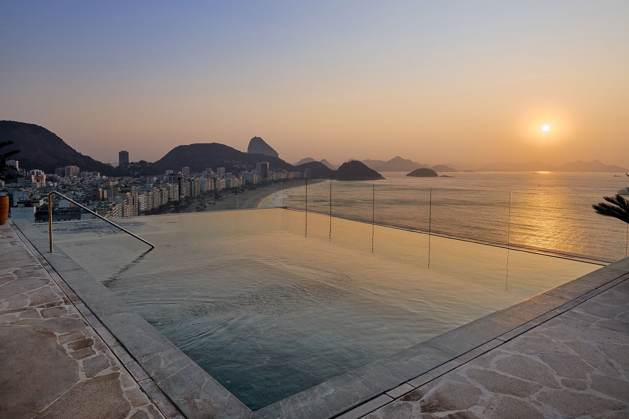 Una piscina con un paisaje urbano y montañas al fondo.
