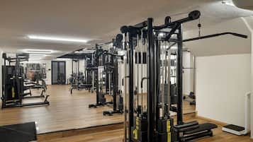 Uma academia com diversos equipamentos de exercícios, piso de madeira e um espelho na parede.
