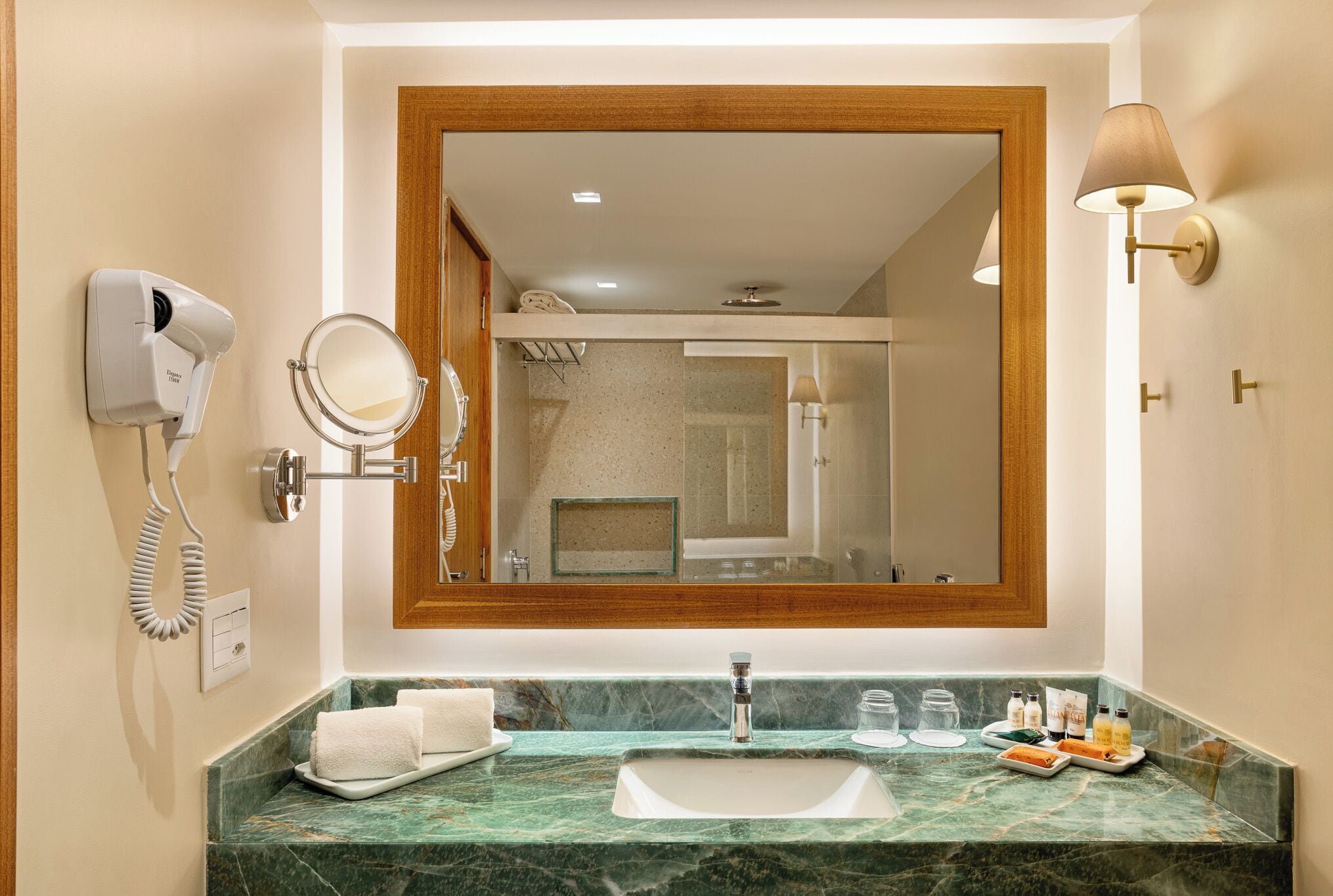 Une salle de bain équipée d’un lavabo en marbre, d’un miroir, d’un sèche-cheveux et d’un porte-serviettes.