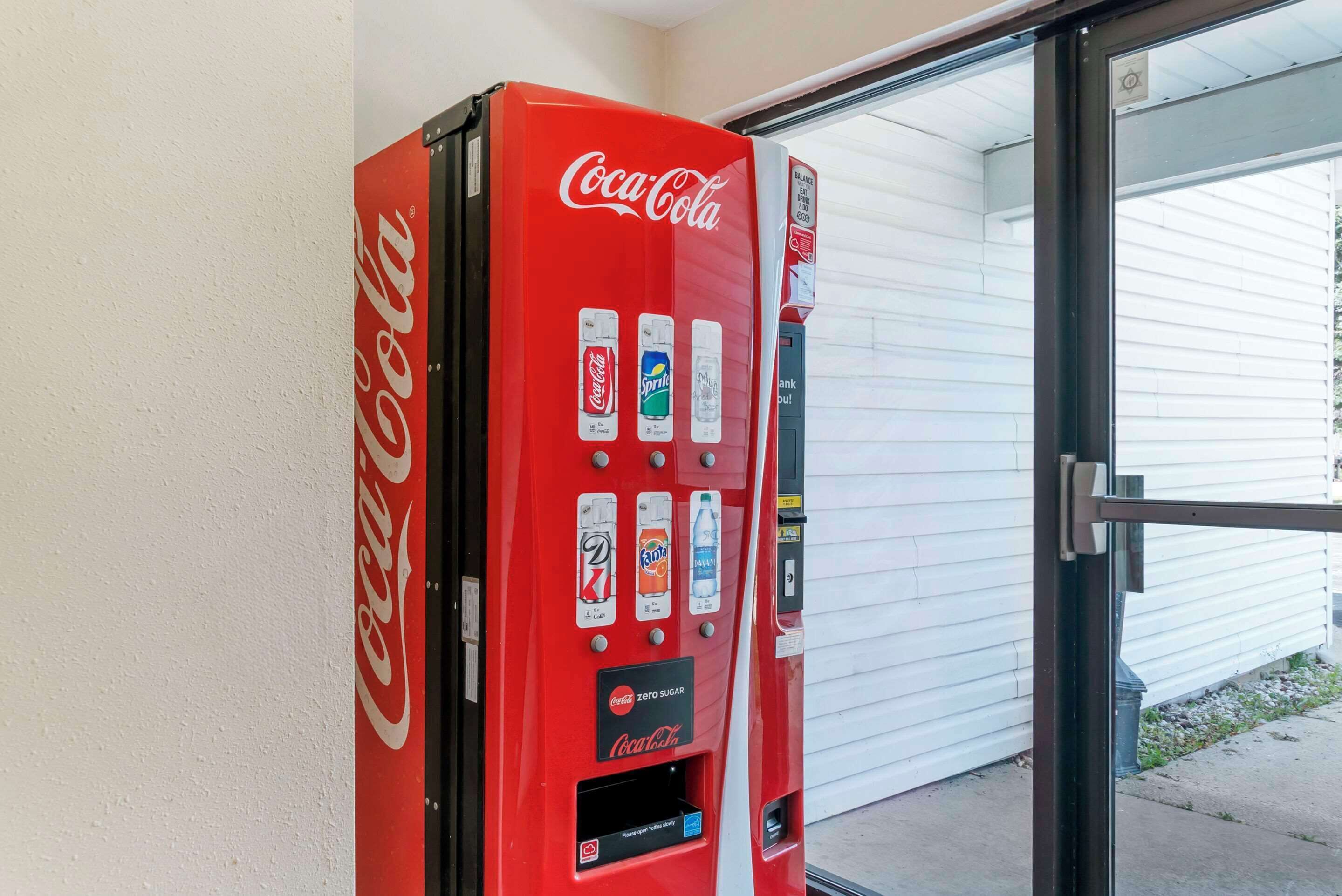 A red Coca-Cola vending machine with various drink options and a Coca-Cola Zero Sugar label.