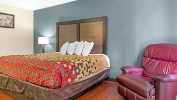 Una habitación de hotel con una cama, un sillón de cuero rojo y una lámpara de pared.