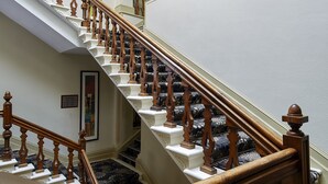A grand staircase with ornate wooden railings and white balusters, leading to an upper floor with a skylight. - The Abbey Great Malvern (Malvern)