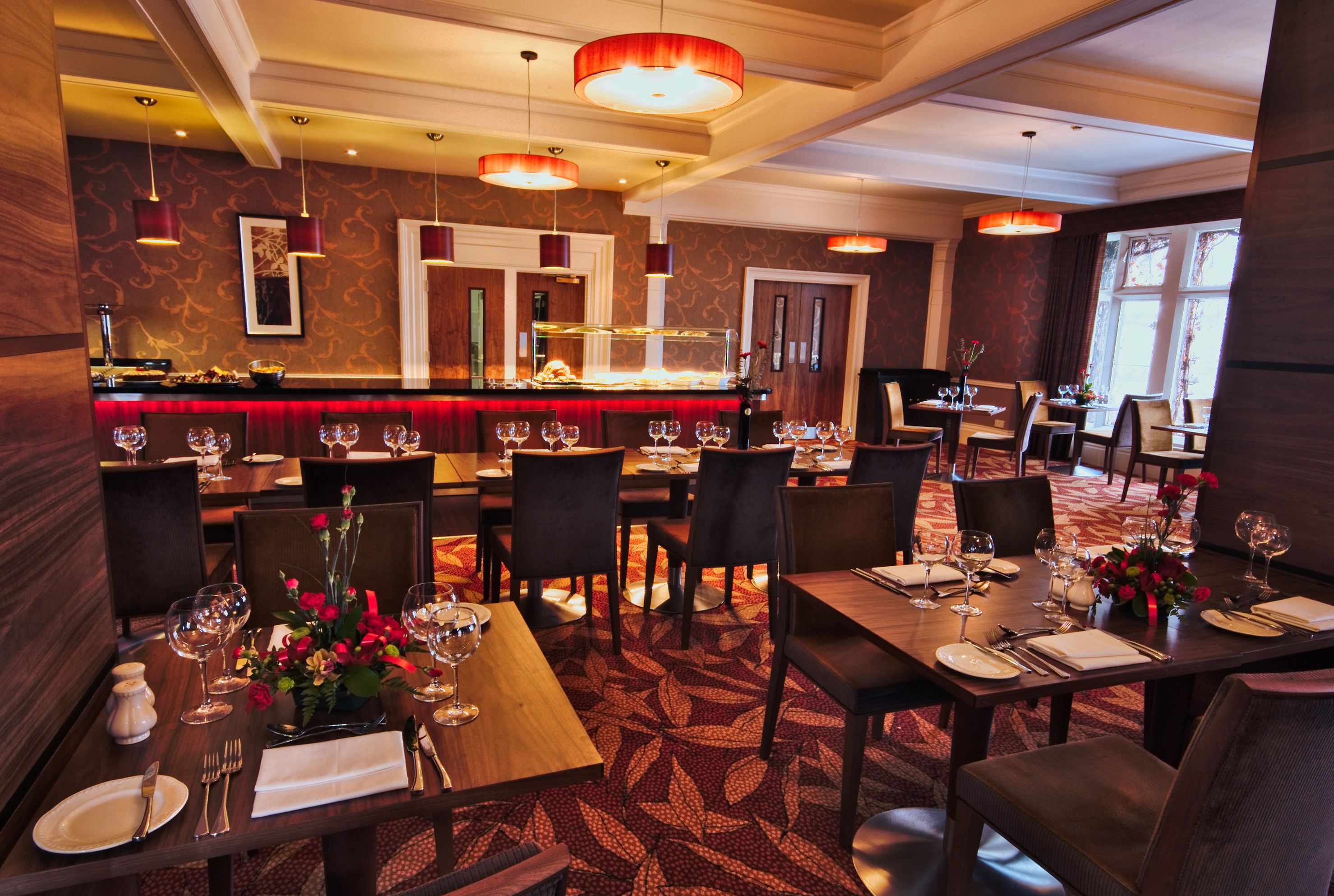 A restaurant with multiple dining tables, chairs, and a bar area.