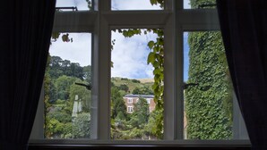 A view through a window with a view of a house surrounded by greenery. - The Abbey Great Malvern (Malvern)
