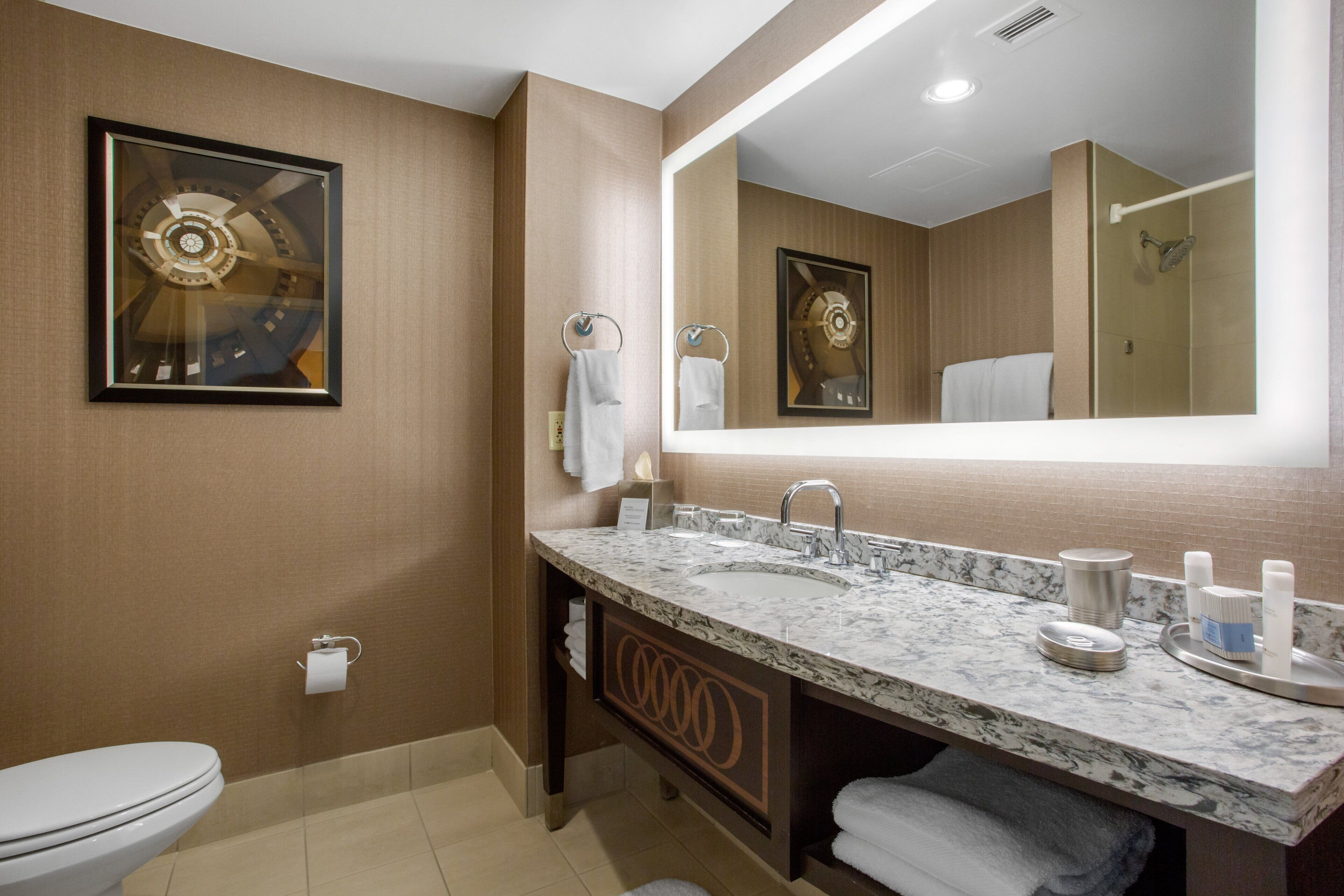 Une salle de bain moderne avec un lavabo en marbre, un grand miroir et une œuvre d’art encadrée accrochée au mur.