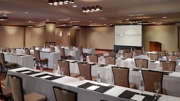 A conference room with multiple tables, chairs, and a projection screen displaying "OMNI Hotels & Resorts Providence | Rhode Island".