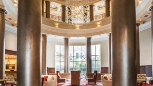 Un vestíbulo imponente con altas columnas, un candelabro y asientos cómodos.