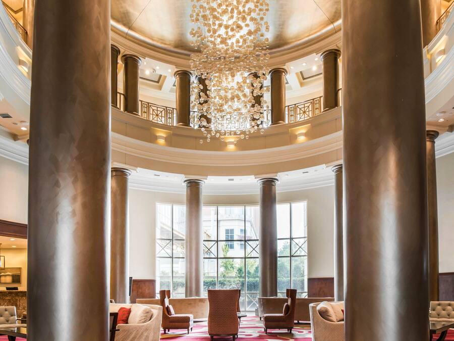 A grand lobby with large columns, a chandelier, and comfortable seating.