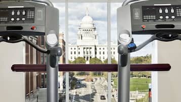 A treadmill with a view of a large building with a dome and a clock tower through a window.