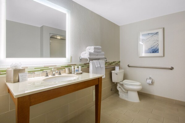 Un baño moderno con un espejo grande, un lavamanos, un inodoro y un pasamanos.
