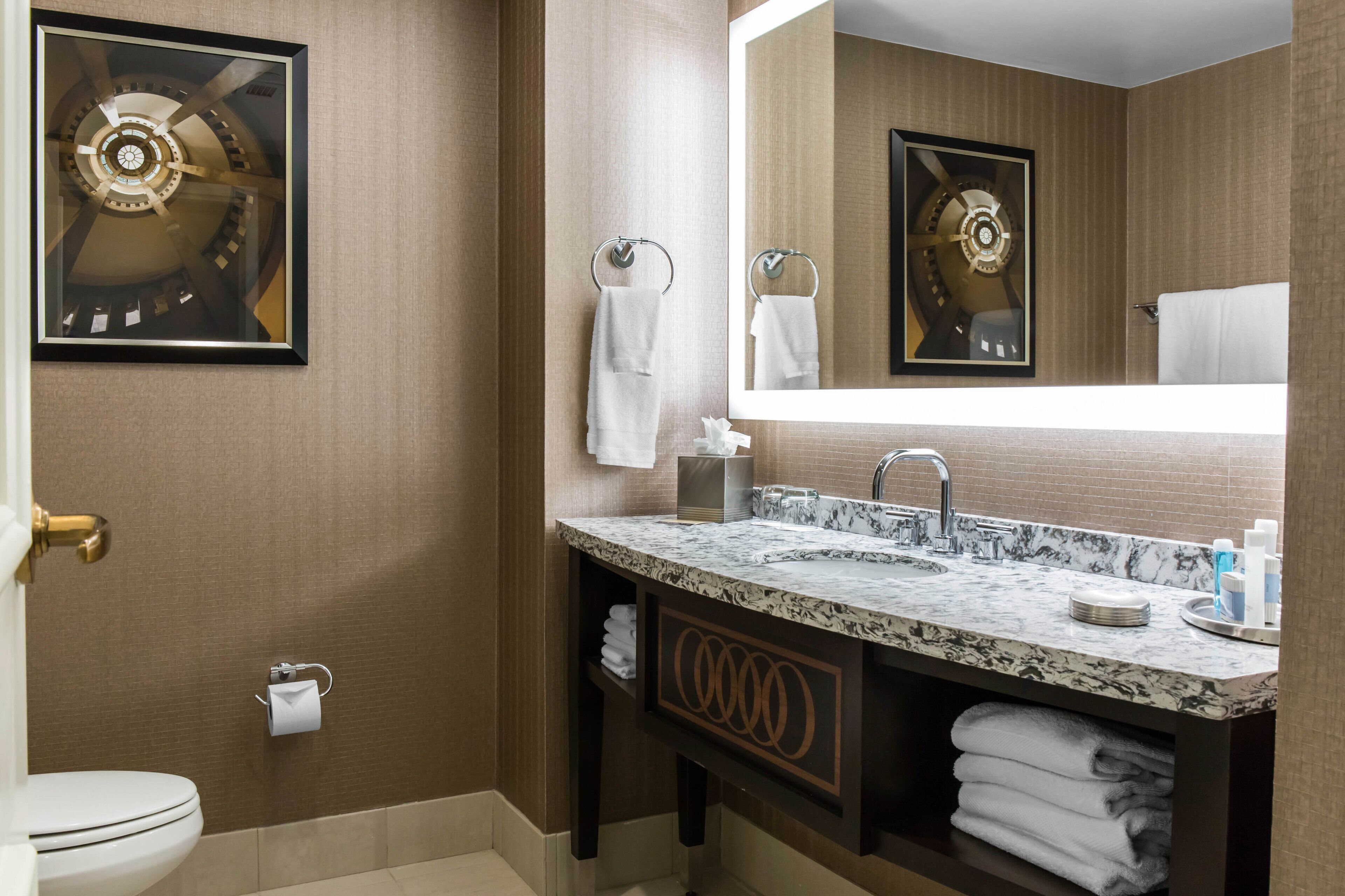 A modern bathroom with a marble sink, a large mirror, and a toilet.