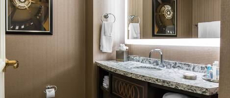 A modern bathroom with a marble sink, a large mirror, and a toilet.