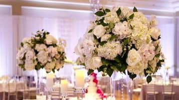 A banquet hall with tables set for a formal event, featuring elegant floral centerpieces and candlelit ambiance.