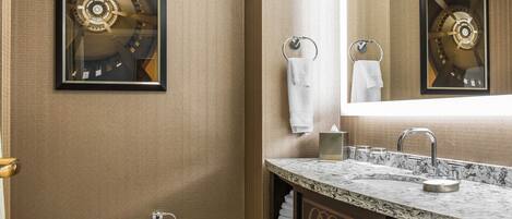 A bathroom with a marble sink, a toilet, and a framed artwork on the wall.