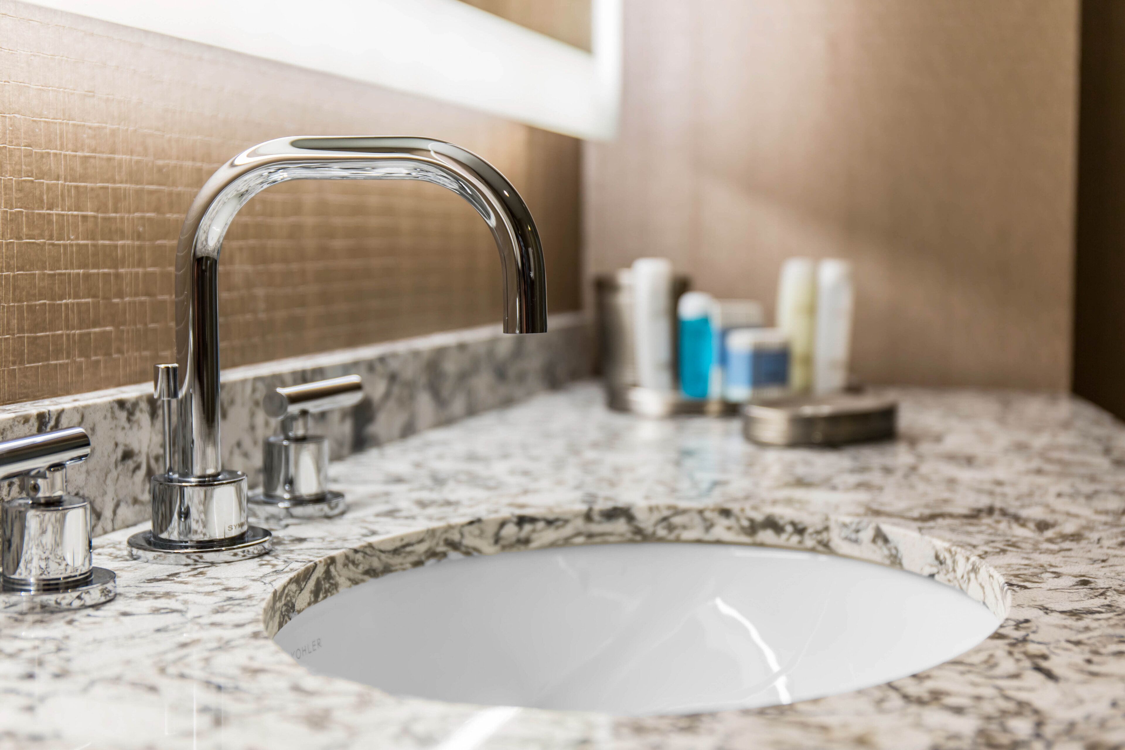 A bathroom sink with a chrome faucet and a marble countertop.
