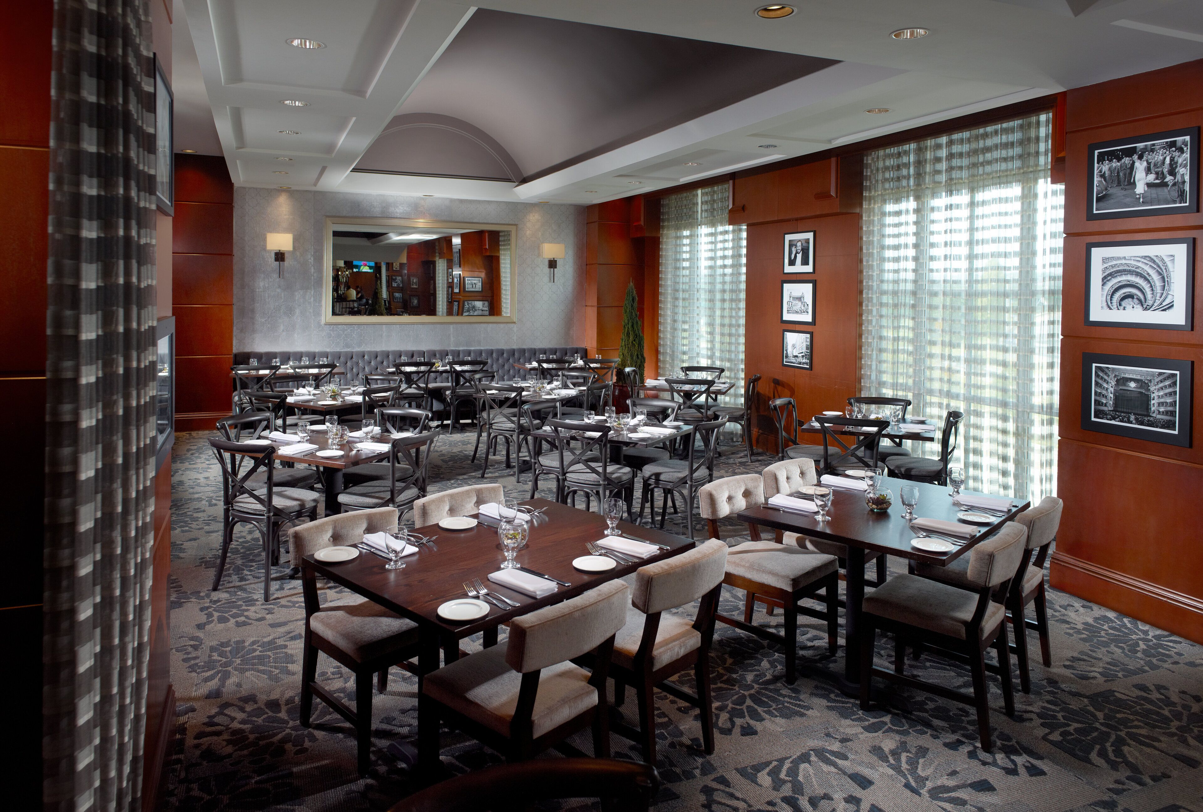 A spacious dining area with multiple tables and chairs, a large mirror, and framed pictures on the walls.
