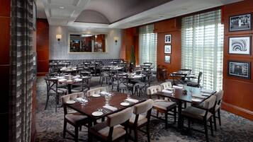 A spacious dining area with multiple tables and chairs, a large mirror, and framed pictures on the walls.