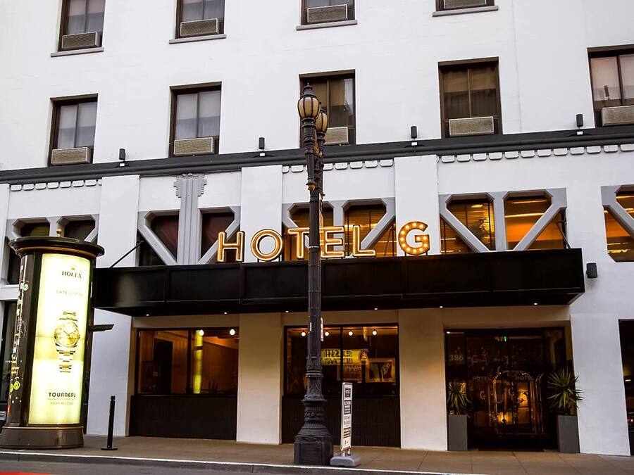Un hotel con un llamativo letrero que dice 'HOTEL G', ventanas grandes y un anuncio de Rolex.