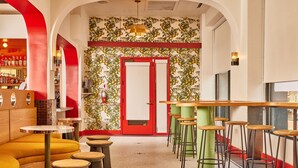 A bar area with stools, a red door, and a wall with a fruit pattern.