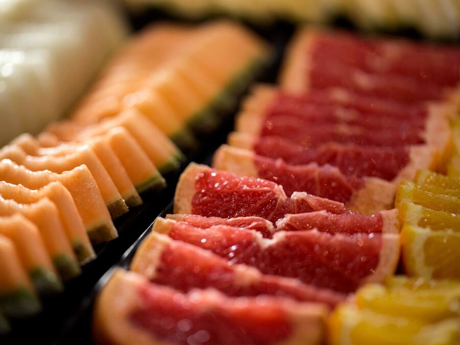 Une vue rapprochée de divers fruits et légumes coupés en différentes formes, probablement dans le cadre d’une présentation culinaire.