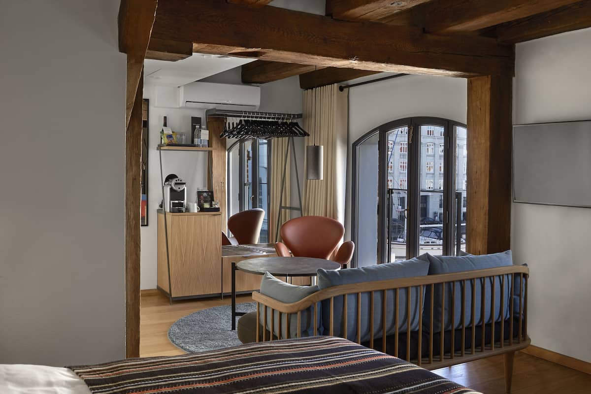 Une pièce confortable avec un berceau en bois, une table à manger avec des chaises, un coin cuisine et une grande fenêtre donnant sur la ville.