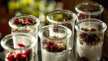 Five glass jars with layered contents, possibly containing dessert or food items, on a reflective surface.
