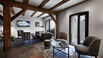 Un espacio habitable amplio con un diseño moderno, que incluye un sofá, sillones, una mesa de centro y un televisor.