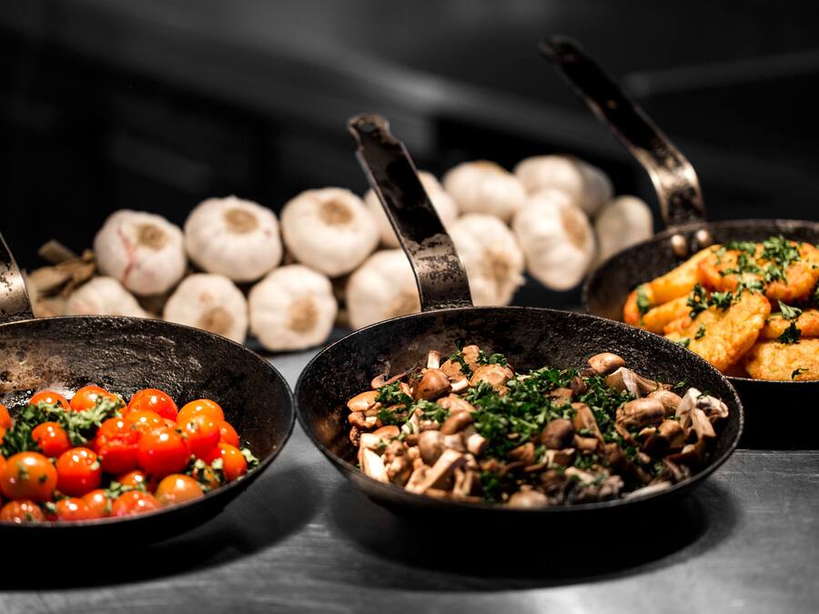 Tres ollas con diferentes alimentos: una con tomates cherry, otra con champiñones y otra con pollo frito.
