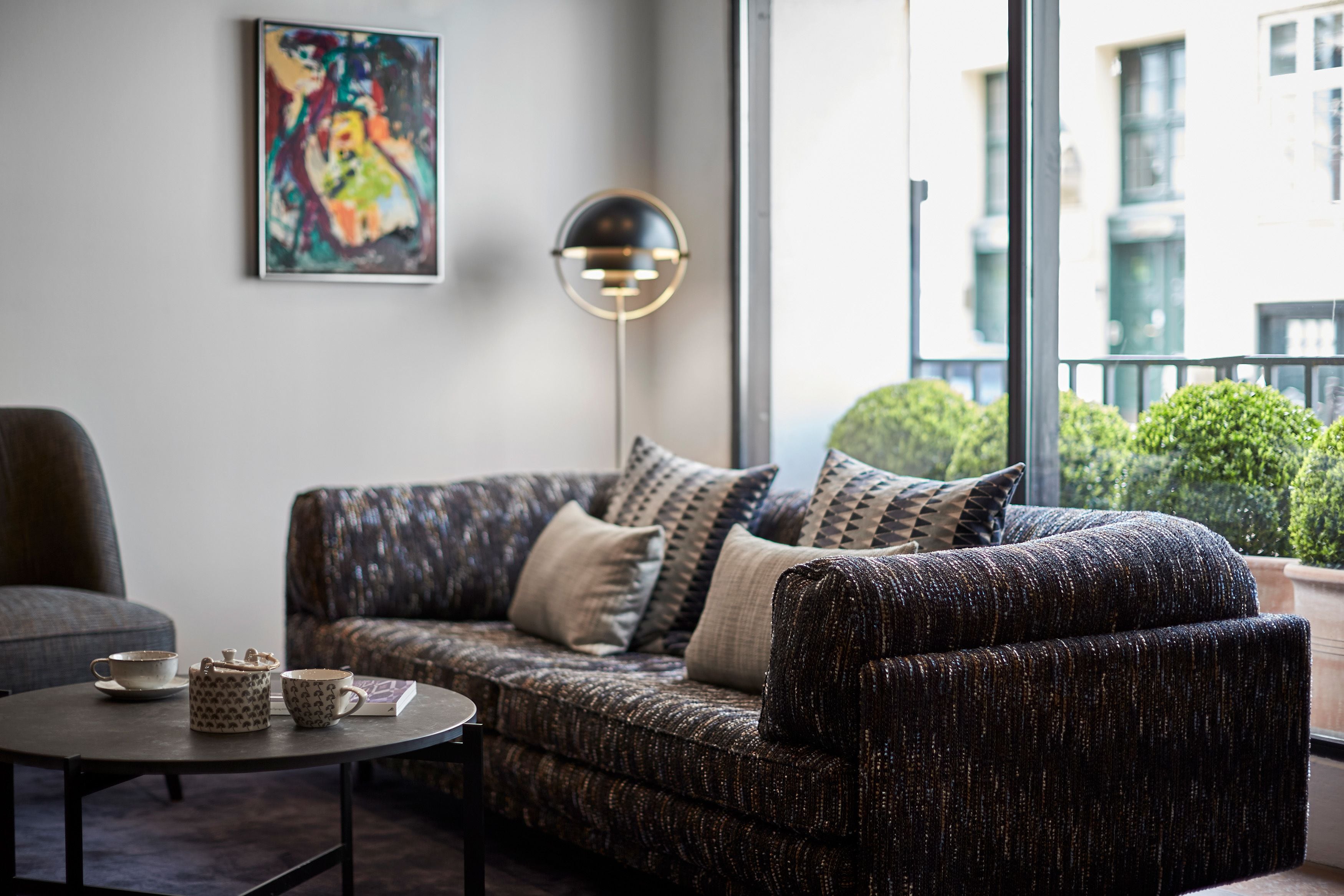 A modern living room with a patterned sofa, a round coffee table, and a floor lamp.