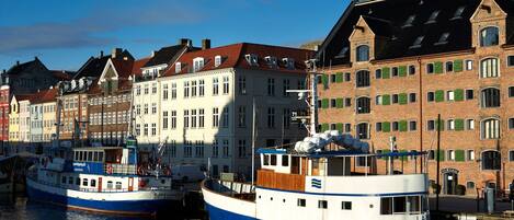 A harbor with two boats docked, surrounded by historic buildings with distinct architectural styles.