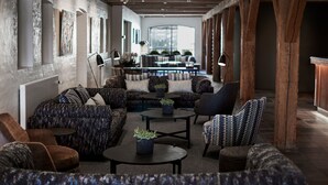 Un área de estar moderna con una variedad de opciones de asientos, incluyendo sofás y sillones, una mesa de centro y un comedor al fondo.