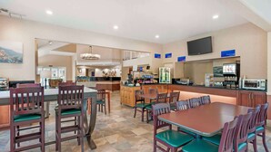 A hotel lobby with a dining area, a reception desk, and a television mounted on the wall.