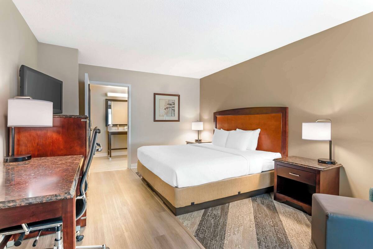 A hotel room with a bed, bedside tables, a desk, and a television.