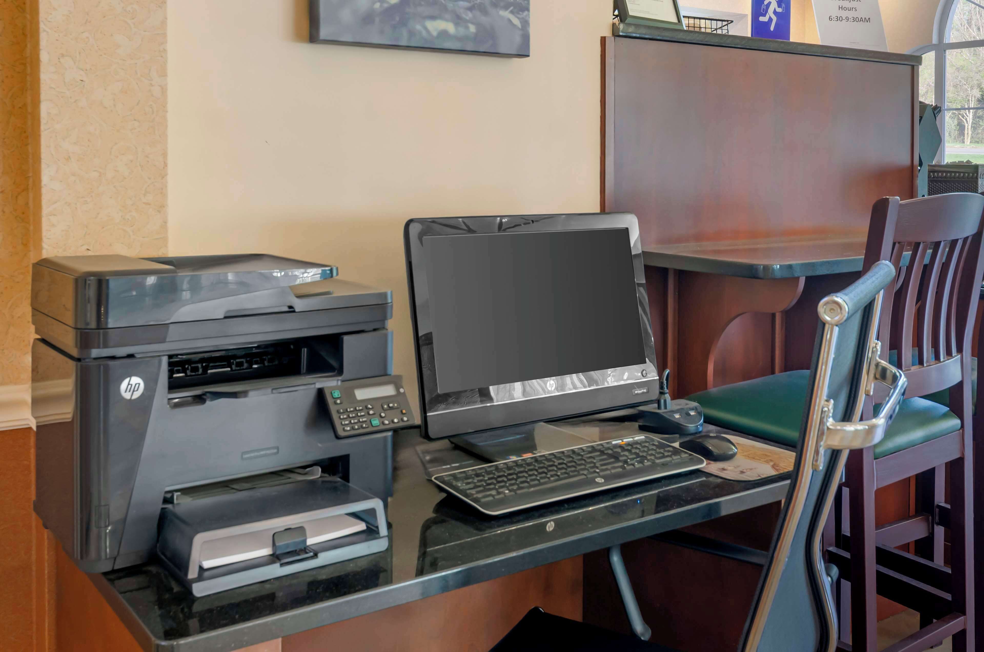 A desk with an HP printer, a desktop computer, and a keyboard.