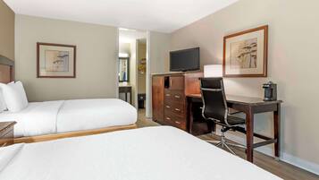A hotel room with two beds, a desk, a chair, a television, and a wardrobe.