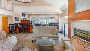 A spacious lobby with a high ceiling, a fireplace, and a seating area with a sofa and chairs.