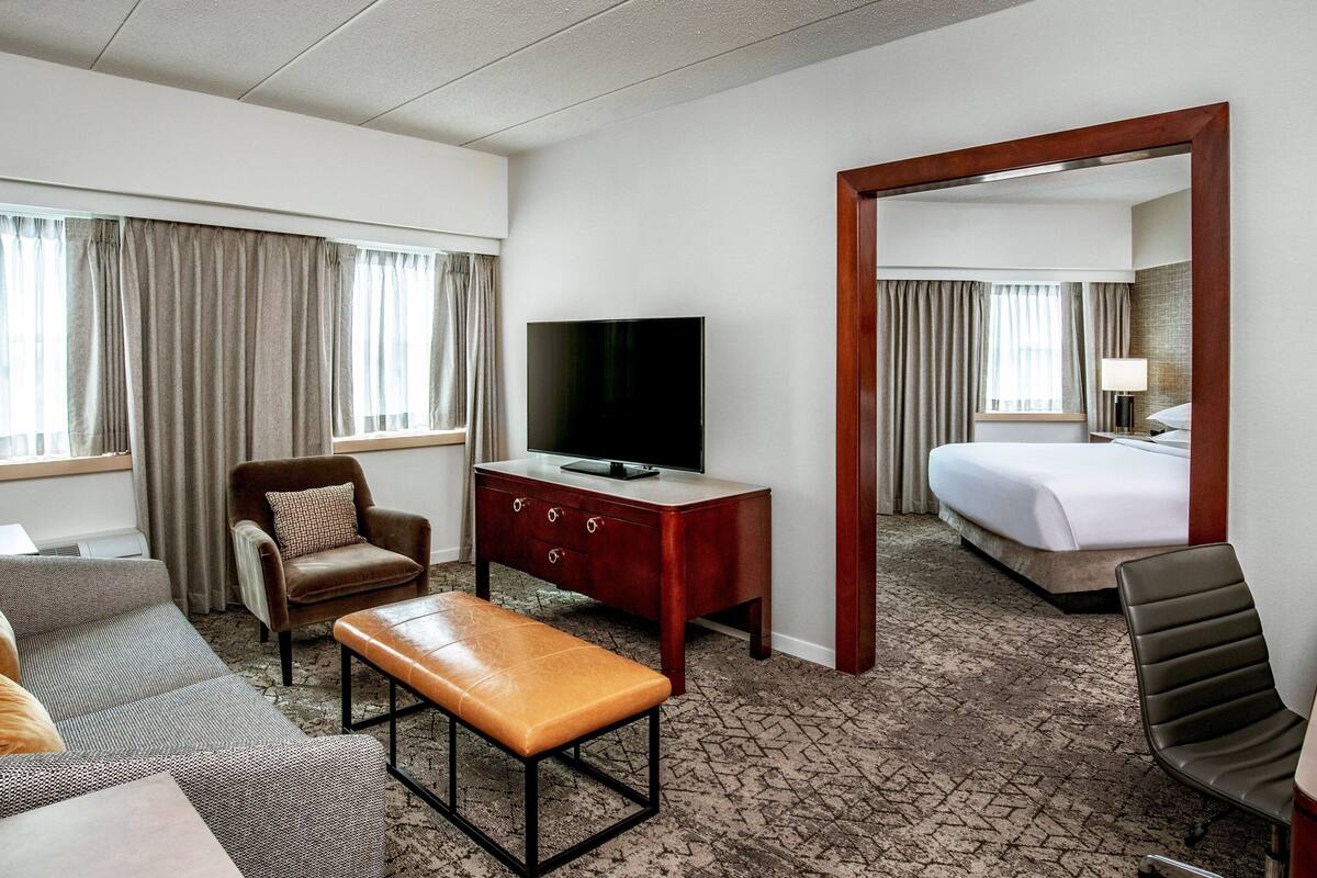 A hotel room with a bed, a TV, a desk, a chair, and a sofa.
