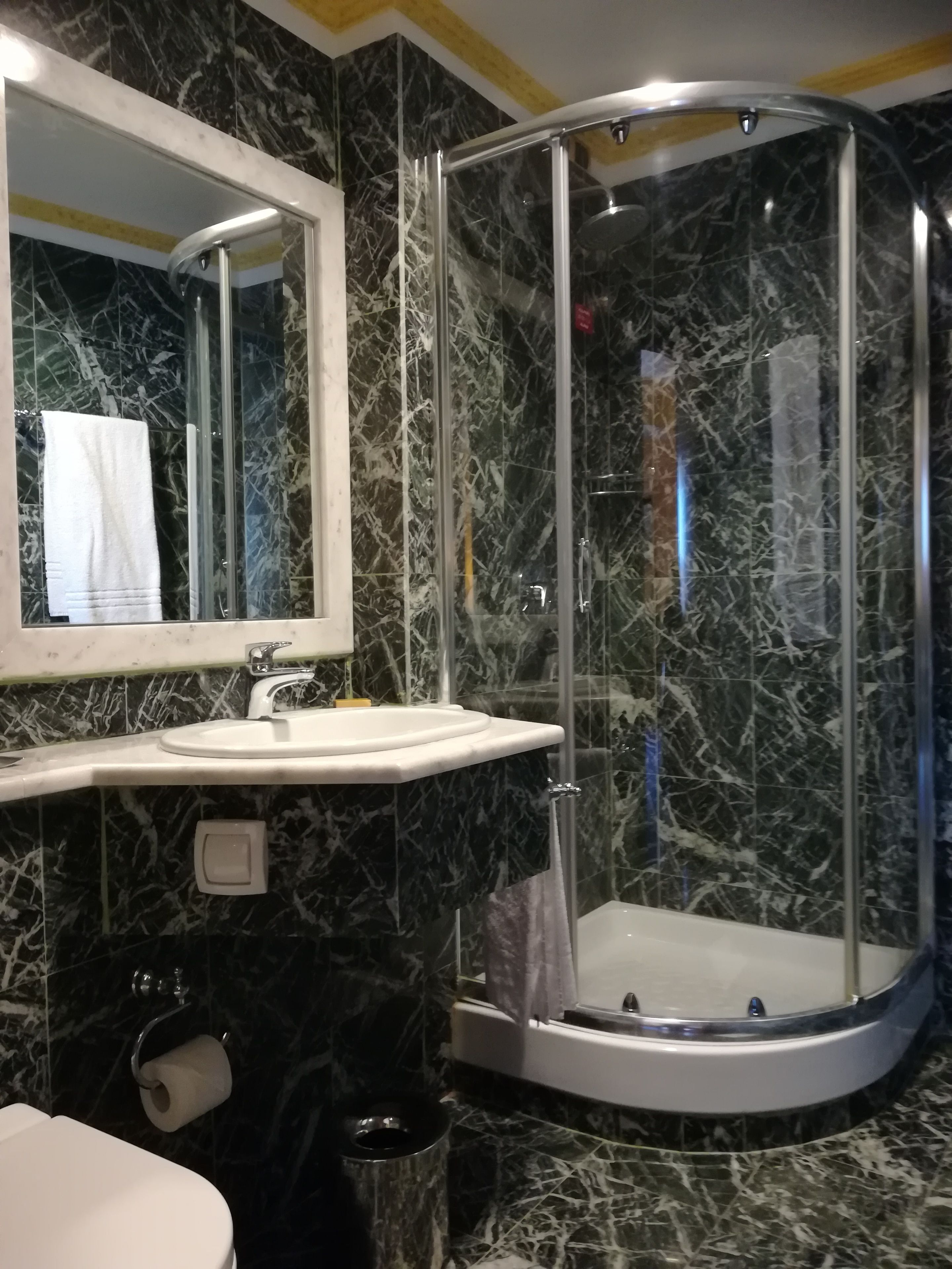 Ein Badezimmer mit Duschkabine, Waschbecken mit Spiegel darüber und Toilette.