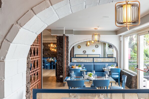 Ein Restaurant mit blauen Sitzmöglichkeiten, einem Backsteinbogen und einer Steinwand.