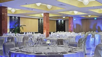 Un salón de banquetes con mesas redondas dispuestas para cenar, con un techo de iluminación empotrada y una llamativa pared decorativa con cascada.