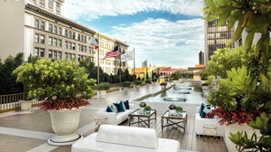 A rooftop terrace with white sofas, a fountain, and potted plants. - Westgate Hotel (San Diego)