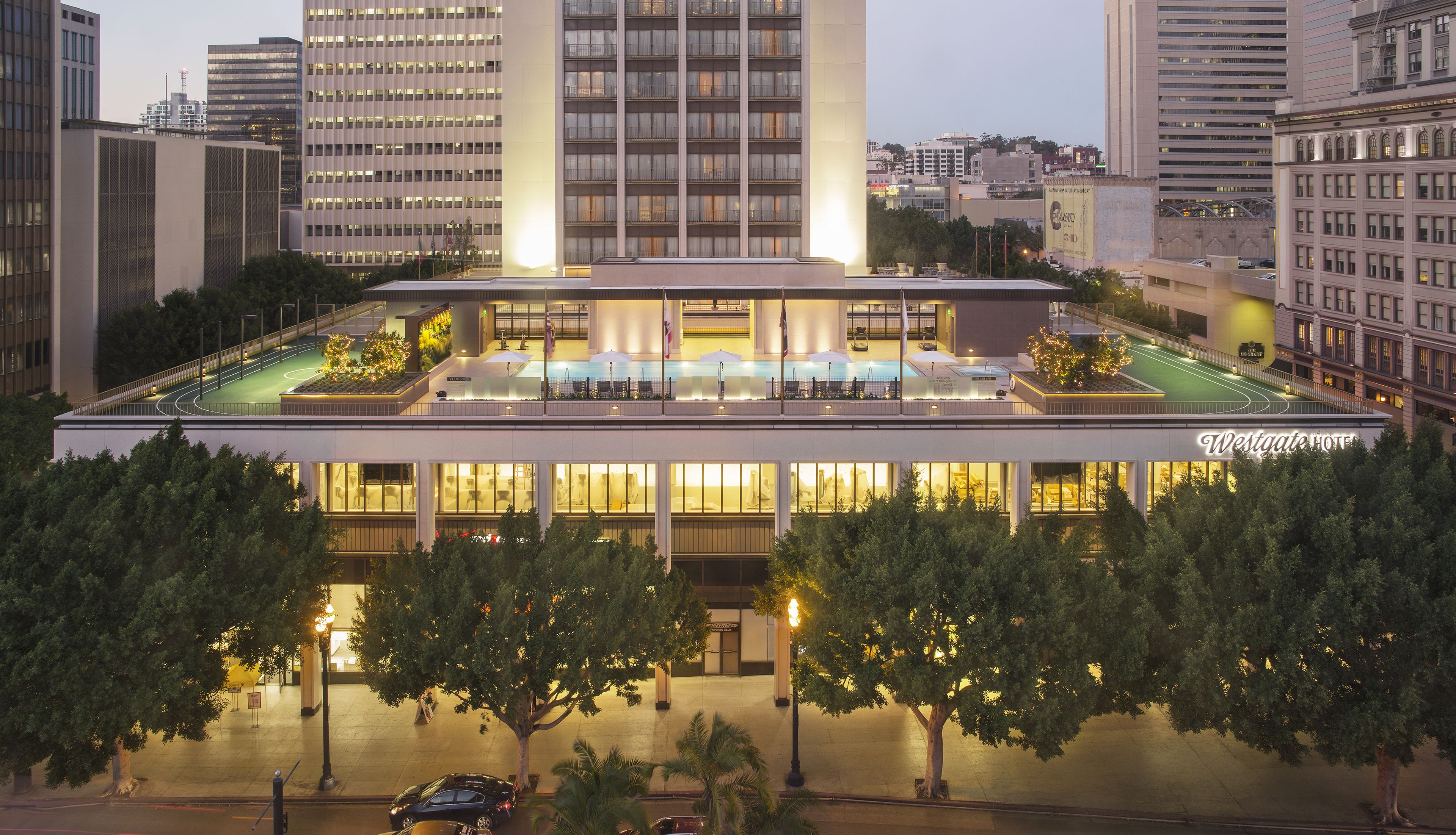 A hotel with a rooftop pool, multiple floors, and a well-lit facade.