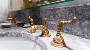 A bathroom with a marble countertop and gold faucets.