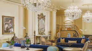 A luxurious room with ornate chandeliers, a grand staircase, and plush seating. - Westgate Hotel (San Diego)