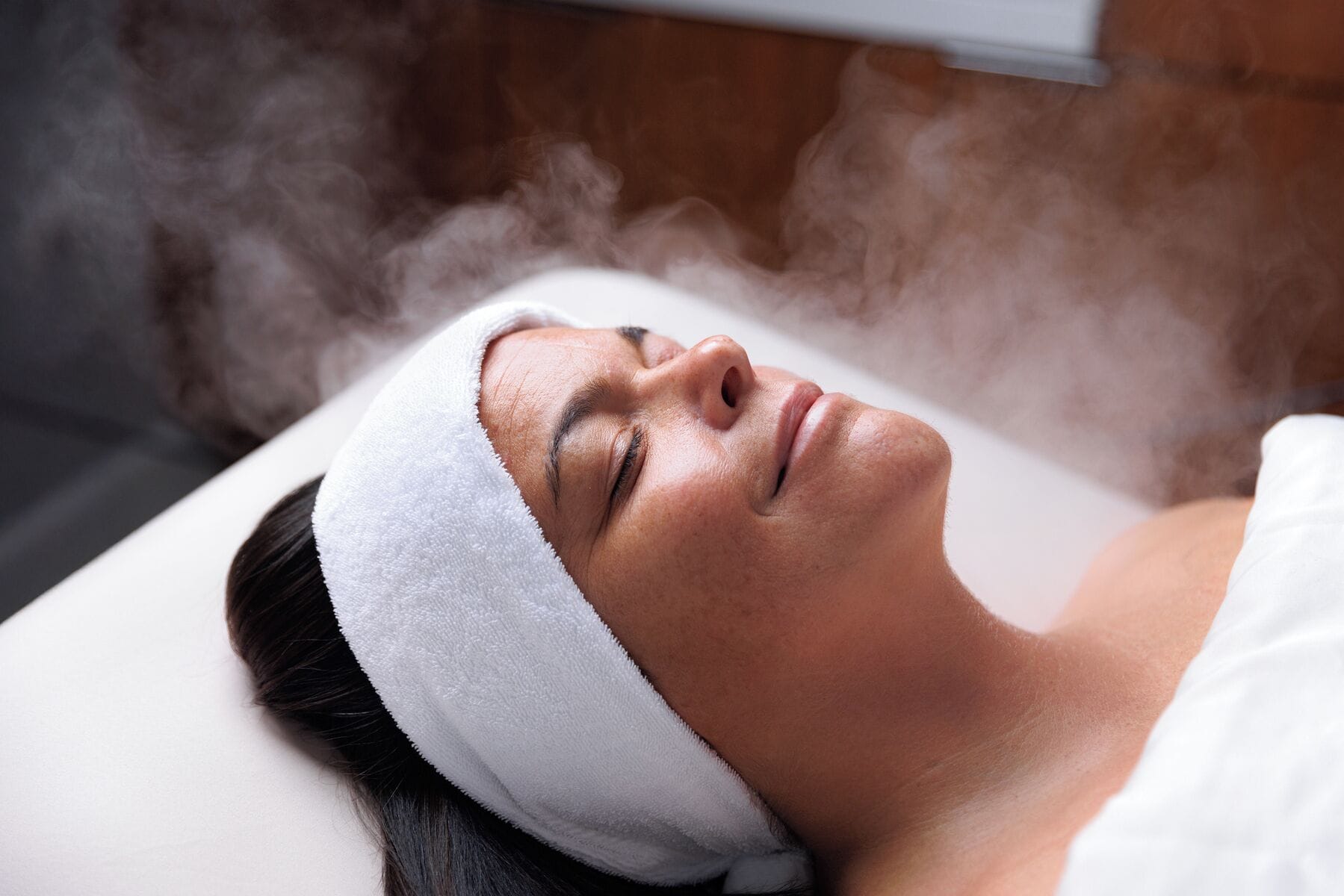 A person lying down with steam rising from their head, suggesting a spa or relaxation setting.