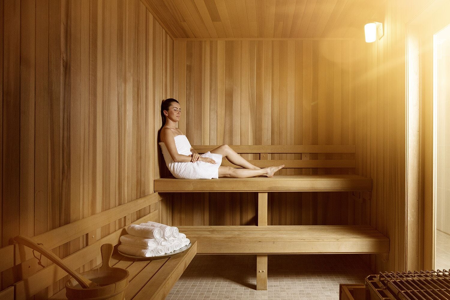 A wooden sauna with benches, a towel rack, and a bench with towels.